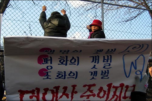 새만금 공사재개 판결이 내려진 21일 오후 정부종합청사를 찾은 계화도 주민들이 경찰의 제지로 농림부로 못들어가게 되자 철조망에 매달려 있다. 